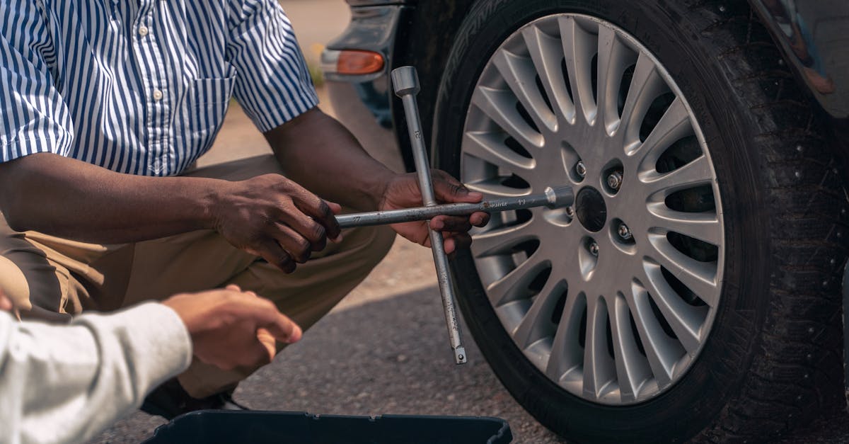 An adult demonstrating how to change a tire to a teenager, focusing on teamwork and learning.